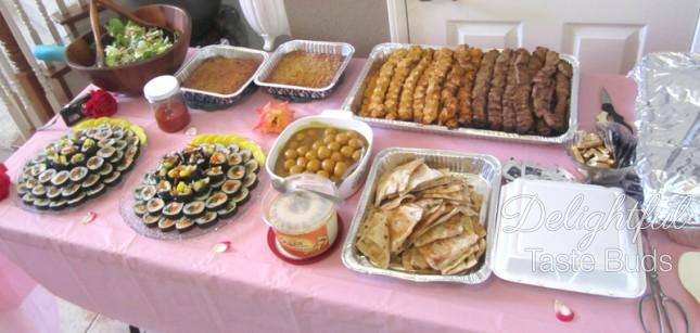 Savory table - kabob, sushi, pita bread, hummus, fish ball curry, huge container of basmati rice (covered in foil)